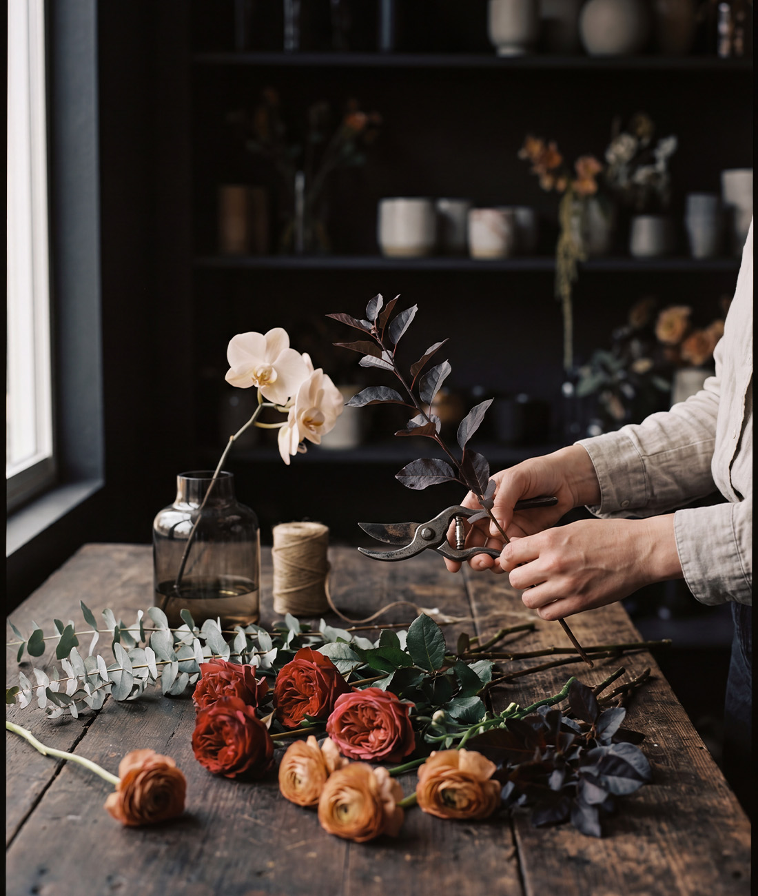 Hands conditioning cut stems on a studio bench.